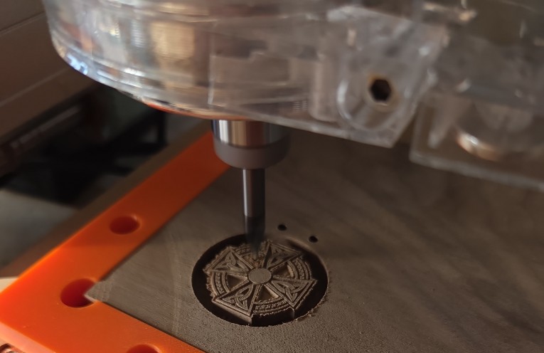CNC carving close-up: warm side lighting, wood chips, carved detail, and real workshop texture.